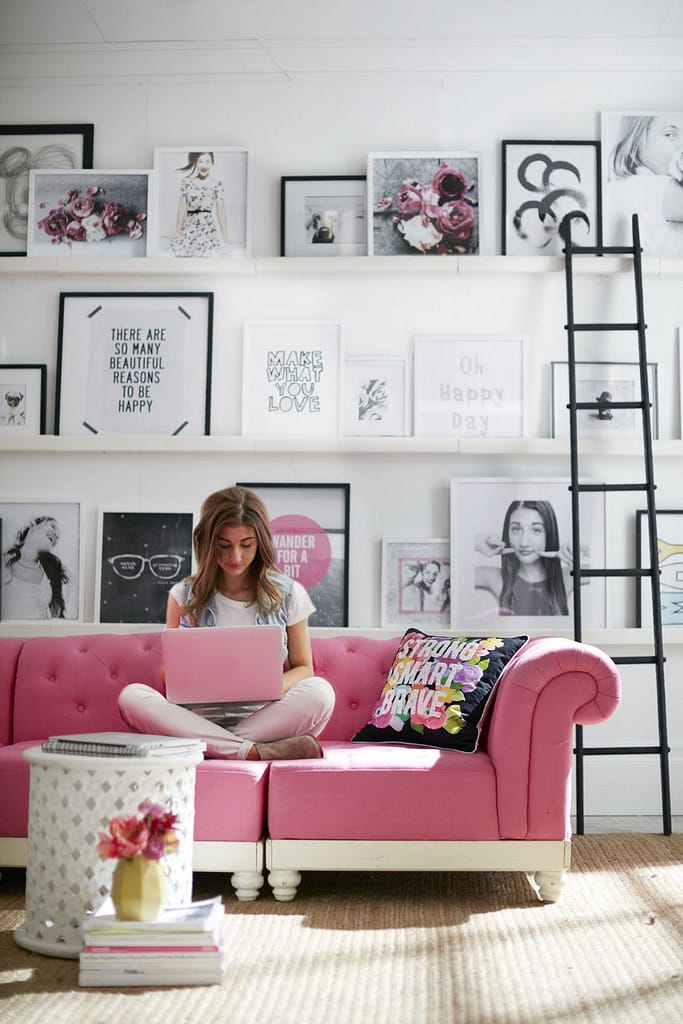 Pink sofa in girly living room with monochrome picture wall