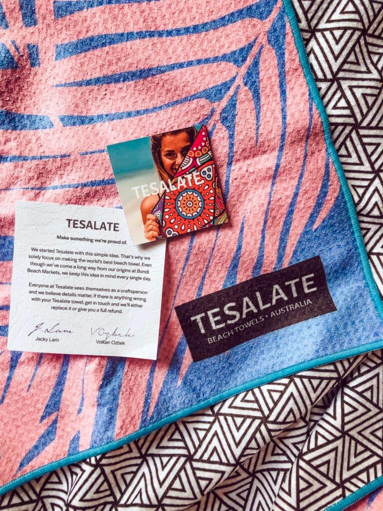 teselate beach towel pink and blue palm printed towel with a black and white triangle geometric print on the reverse